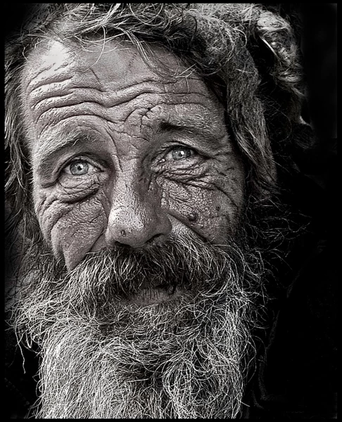 Taken in the street in Cassis in France. This was a tramp who was resting from the hot sun outside a shop. I asked if I could take his picture and gave him some money for his time. I wanted to do a mono but with a slight hint of colour _ especially the eyes. This is a tight crop on his face. Natural light only.