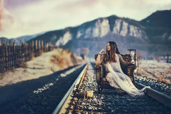 This is a conceptual shot over the theme of the passing of Time. The railway, the level passage is a place where we usually don't stop, stand or sit. The girl represents those who seek deeper and stop where others don't, wait while others rush, search for things when and where others won't. She holds an hourglass, symbol of the passing of time. If you stop, you can hold time, maybe just for a while. 