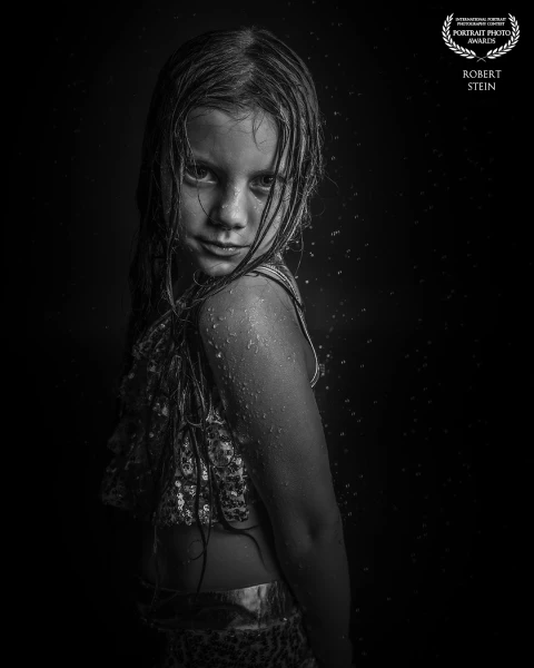 In my portrait 'Silent Resilience,' I capture a child emerging from water, their gaze penetrating di...