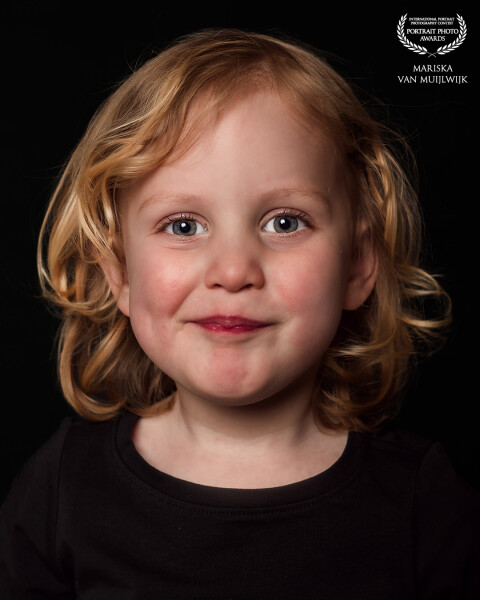 A minimalistic portrait showing a girl with a steady, open expression. The soft lighting and clean background keep all attention on her face.