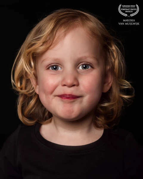 A minimalistic portrait showing a girl with a steady, open expression. The soft lighting and clean background keep all attention on her face.