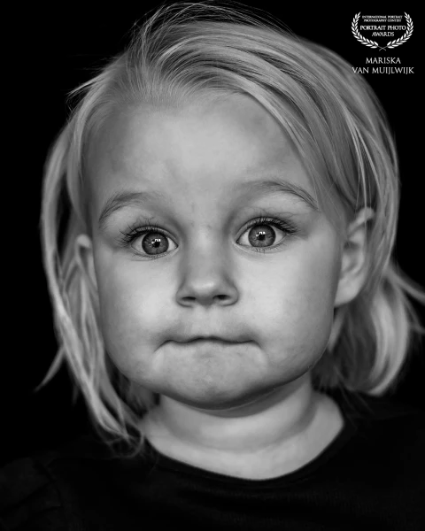 A simple, natural portrait of a young girl. Photographed in black and white, with focus on her direc...