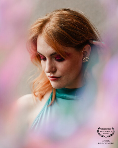 Surrounded by soft, pastel-colored blur, she appears almost wrapped in a dreamy haze. The tones crea...