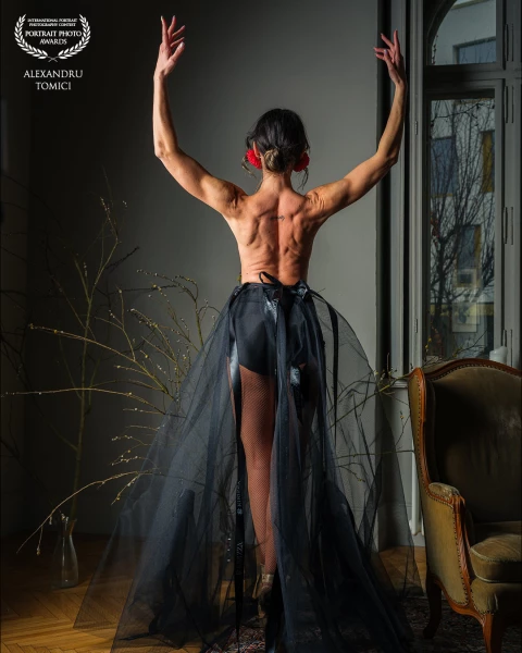This striking portrait captures a dancer poised in a moment of expressive grace. Seen from behind, h...