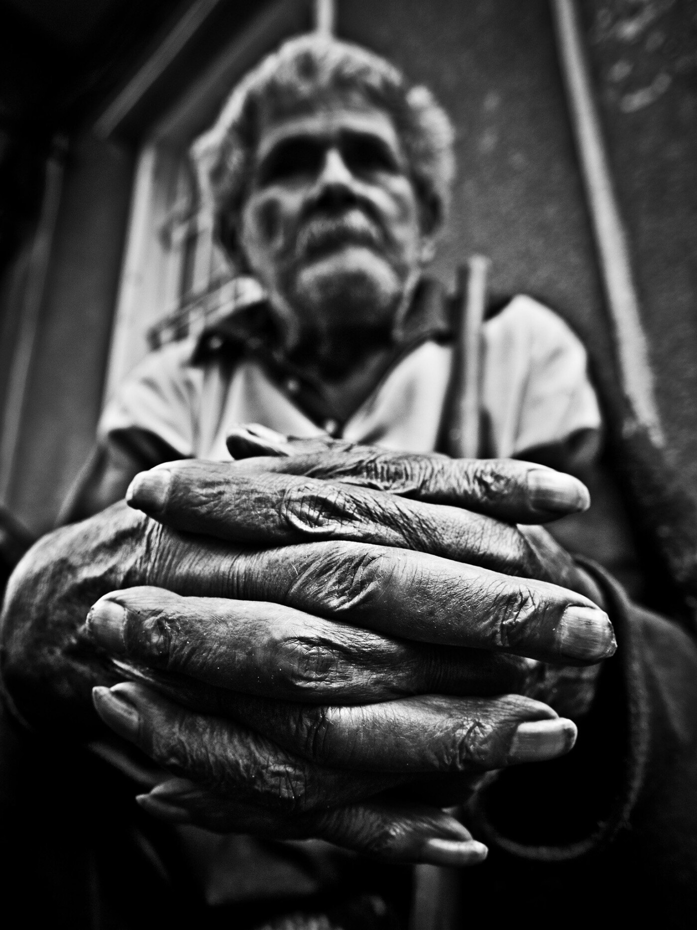 Candid portrait of a street beggar under natural light. The focus was on his rugged hands, his only literal mean of survival. 