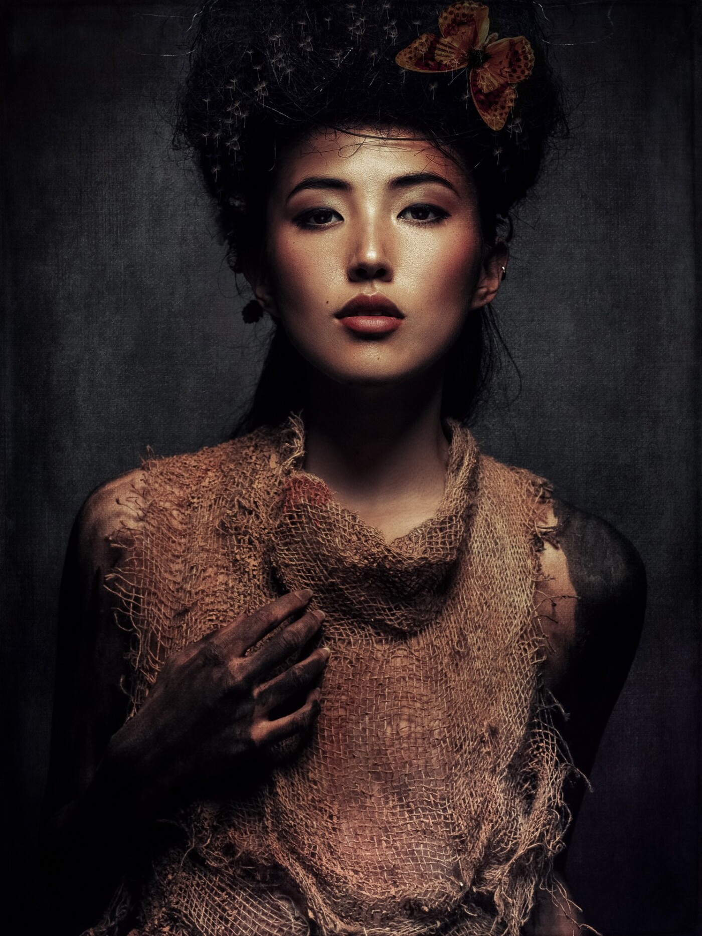 The Model Änna Lou has a wonderful exotic face and charisma. I wanted to try a special, unusual styling, that focusses on the exoticism and the unusual. I was curious to see whether it would be possible to use a bag-like material and still make an elegant image. The light came from above and the brightness of the face draws attention.
