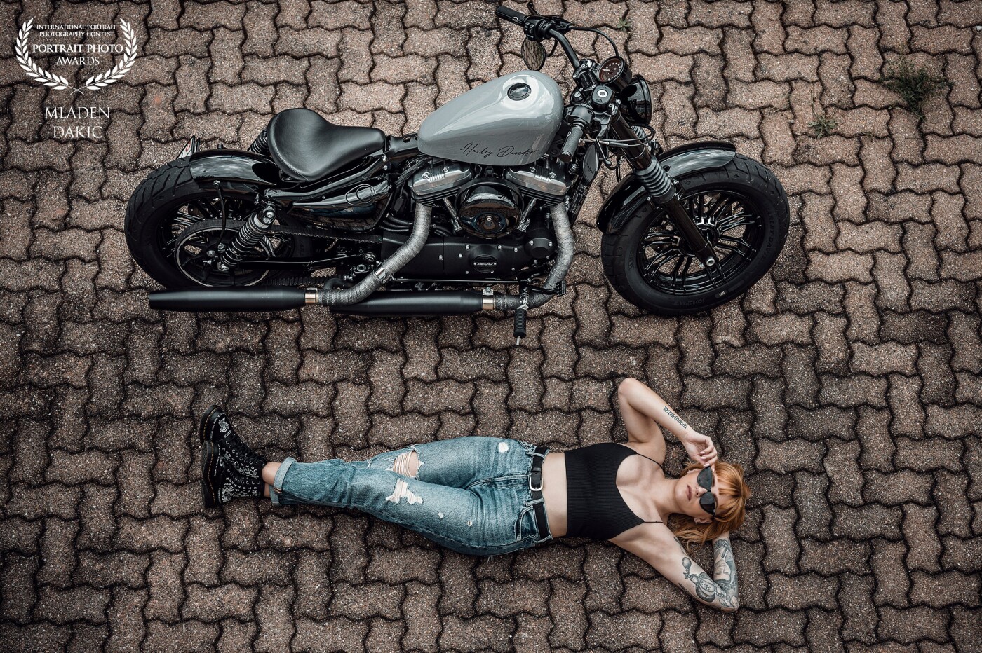 My Model Andrea owns this magnificent Bobber style Harley Davidson. The Mission was to make some cool photos of her with her Baby. One of them is this stunning picture of her laying by her Motorcyce. I love it.<br />
I used natural light only.