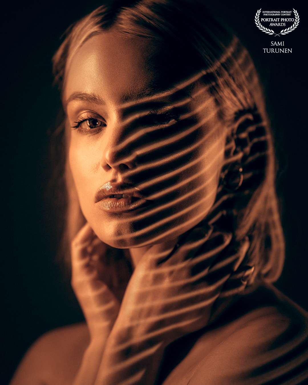 This photo is a combination of led tubes and video projector (home-made-gobo). Stripe gobo gives nice shapes and flows through model's (elegant Veera Kankare) natural curves. Expression and tones are perfect for this kind of moody photo.