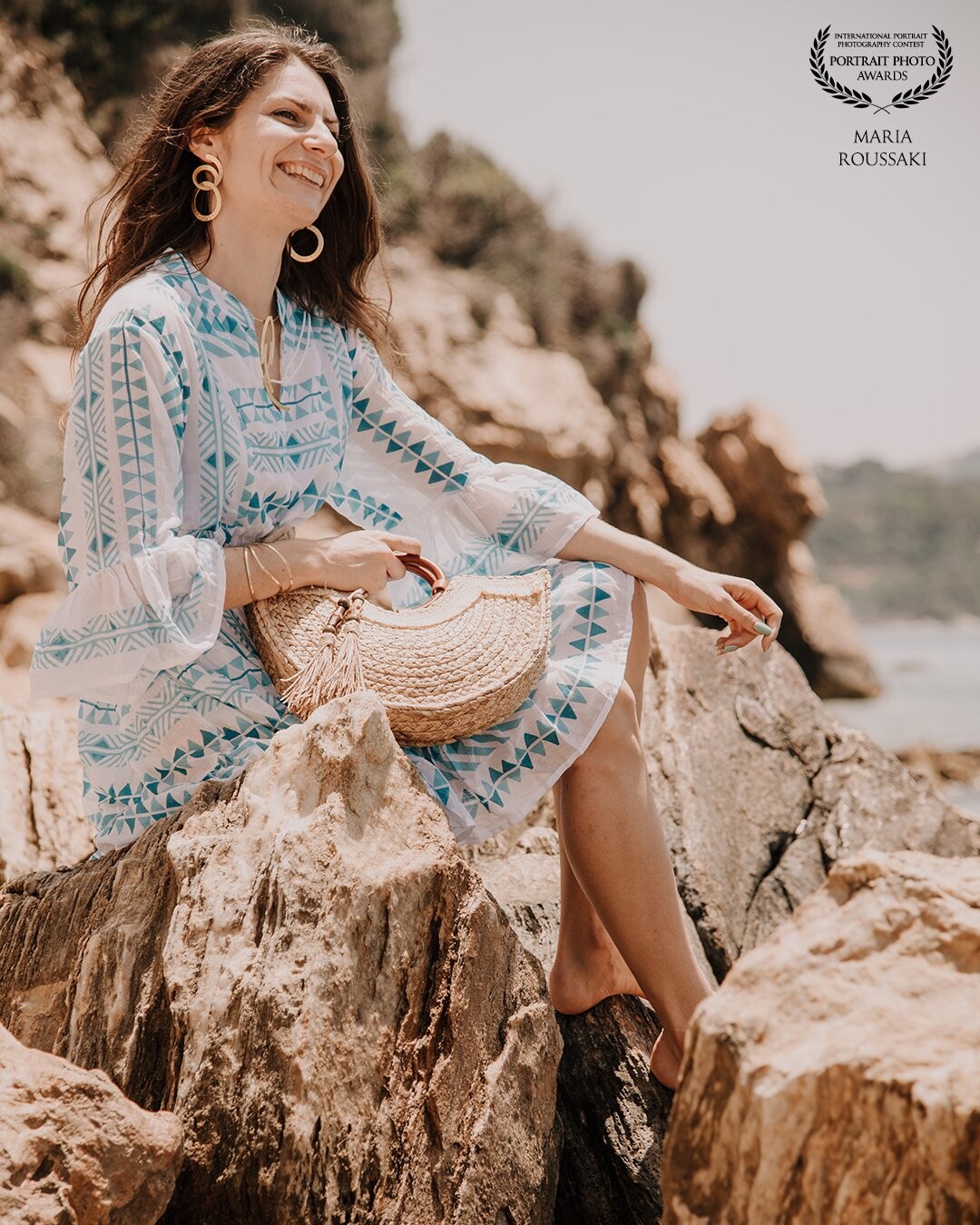 “Can you capture the Greek summer style in only one picture?” is what the client asked us, and we accepted the challenge. <br />
Blue and white dress, check. The Greek sun providing warm colors, check. Beautiful but rough and rocky beach, check. What was missing? The genuine smile that everyone gets automatically the moment they arrive to a Greek island. Well… Check.