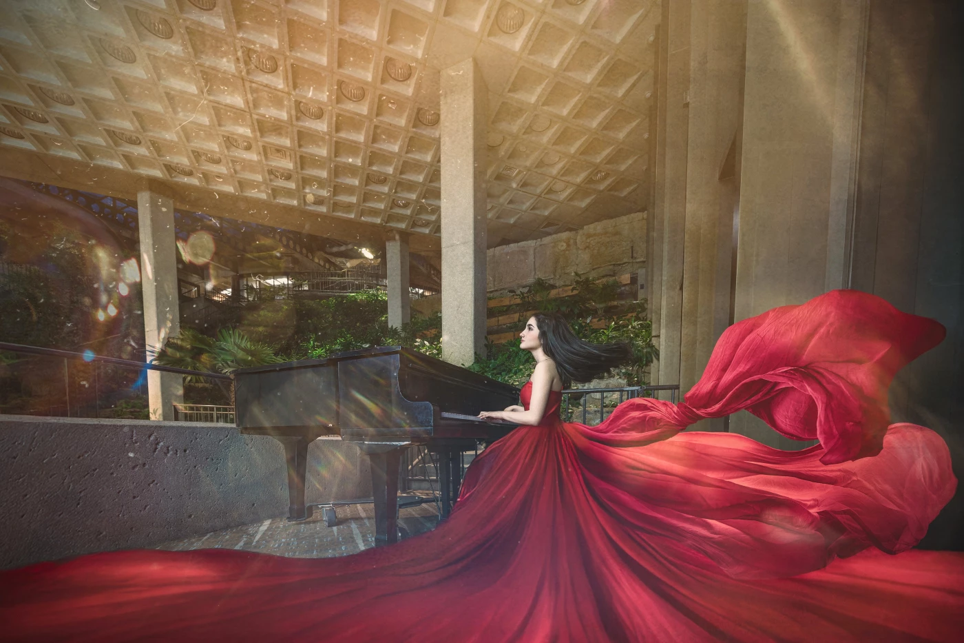 This captivating photograph features a woman in a flowing red gown seated at a grand piano within a...