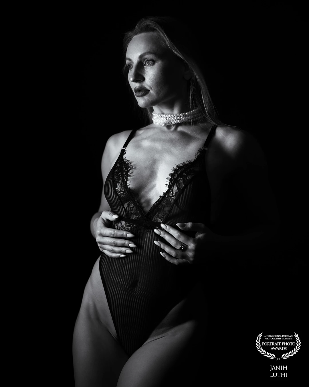 In shadows deep, she finds her grace, <br />
A moment captured, a timeless face. <br />
With lace and light, a dance so fine, <br />
In monochrome, her beauty shines. <br />
<br />
Whispers of elegance, soft and bold, <br />
Stories untold in the curves they hold. <br />
A pearl adorns, a touch of flair, <br />
In stillness, she breathes a silent air. <br />
<br />
Artistry flows where shadows play, <br />
A timeless muse in the night’s ballet. <br />
Embracing allure, both fierce and soft, <br />
In this serene frame, dreams lift aloft.