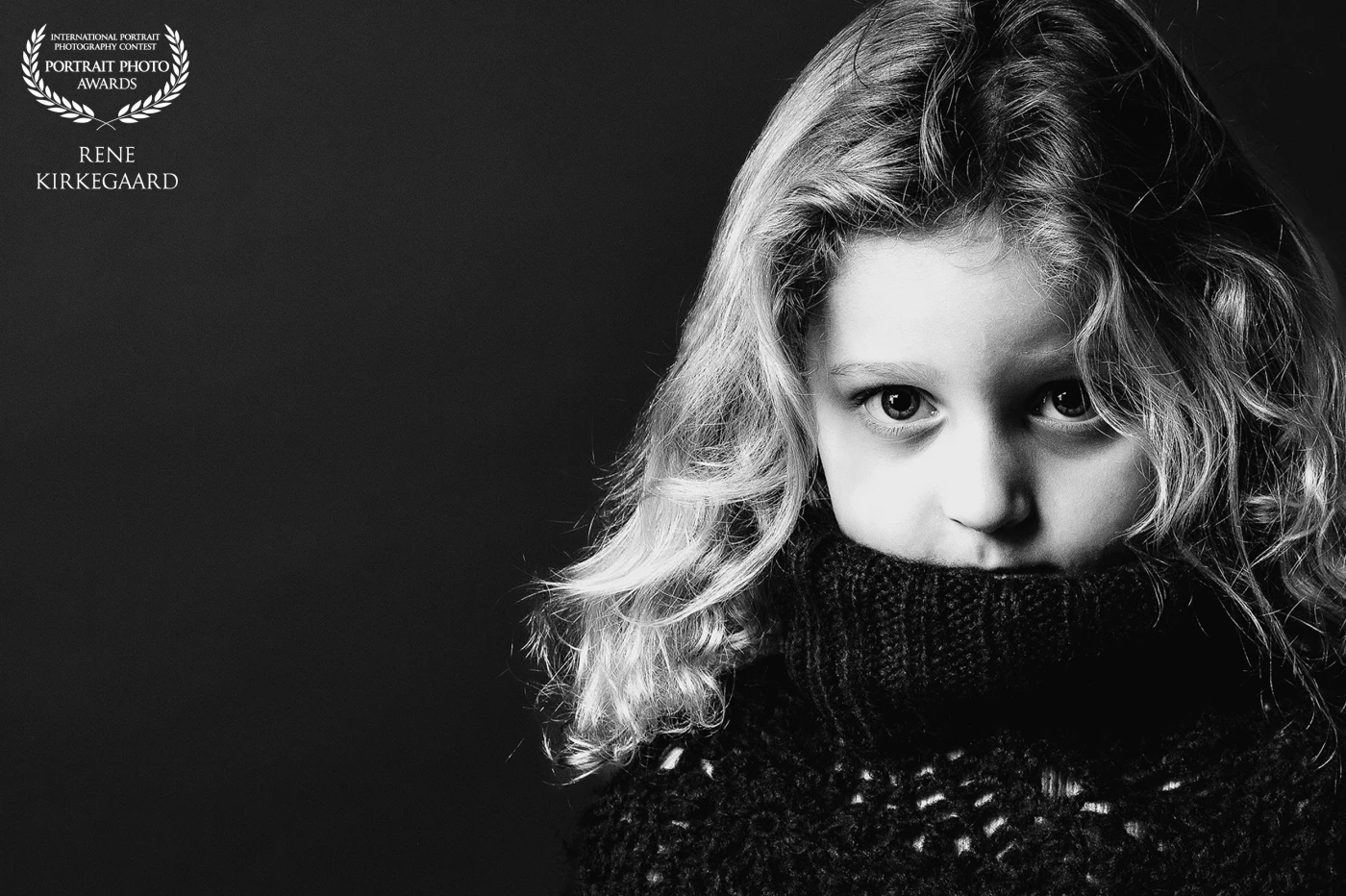 Shy, yet curious about the camera and the photographer.<br />
This portrait captures a beautiful girl with her chin tucked into her sweater, offering a strong and captivating gaze. Her subtle posture and intense eyes made for a compelling image.