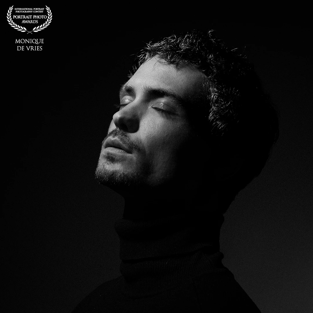 "Silence in Shadow" (man with closed eyes)<br />
A study in solitude and surrender. With his eyes closed, the subject turns inward, illuminated just enough to hint at the contours of vulnerability and strength. This image is about the spaces we hold inside ourselves—where light and shadow are no longer opposites, but partners in presence.