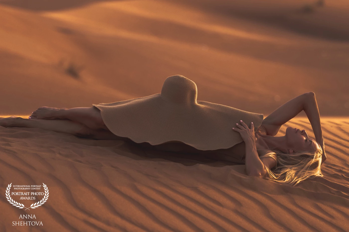 Becoming the Sand-<br />
In the heart of the desert where silence speaks in golden tones , a woman is blending with the dunes . A moment where the human spirit merges with the rhythm of the world , becoming one with the sand