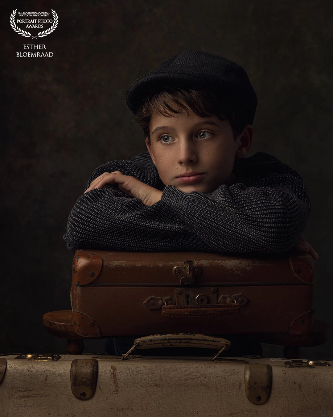 His gaze drifts beyond the horizon, as if the suitcases aren’t filled with belongings, but with stories yet to begin. <br />
A portrait of an boy, standing before the camera for the very first time, captured in the light of the old masters.<br />
<br />
Model: Nicolas<br />
Photo & edit: @estherbloemraad.fotografie